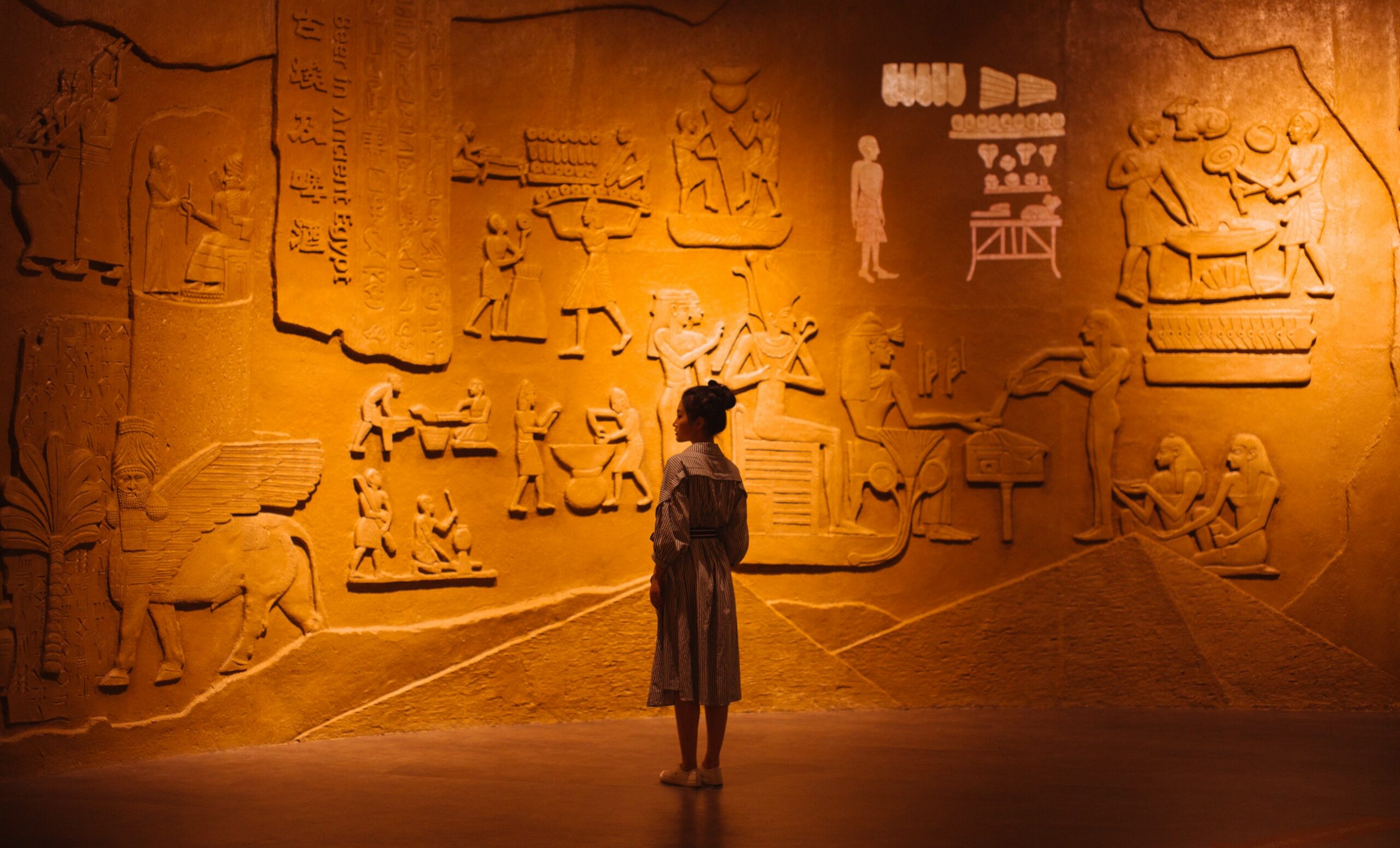 Woman standing near old stone wall with carved images