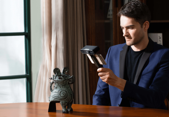 Man pointing a handheld 3d scanner at an object